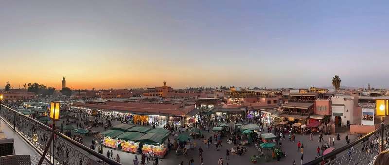 Jemaa el-Fna al atardecer, los puestos iluminándose mientras el cielo cambia sobre la Koutoubia
