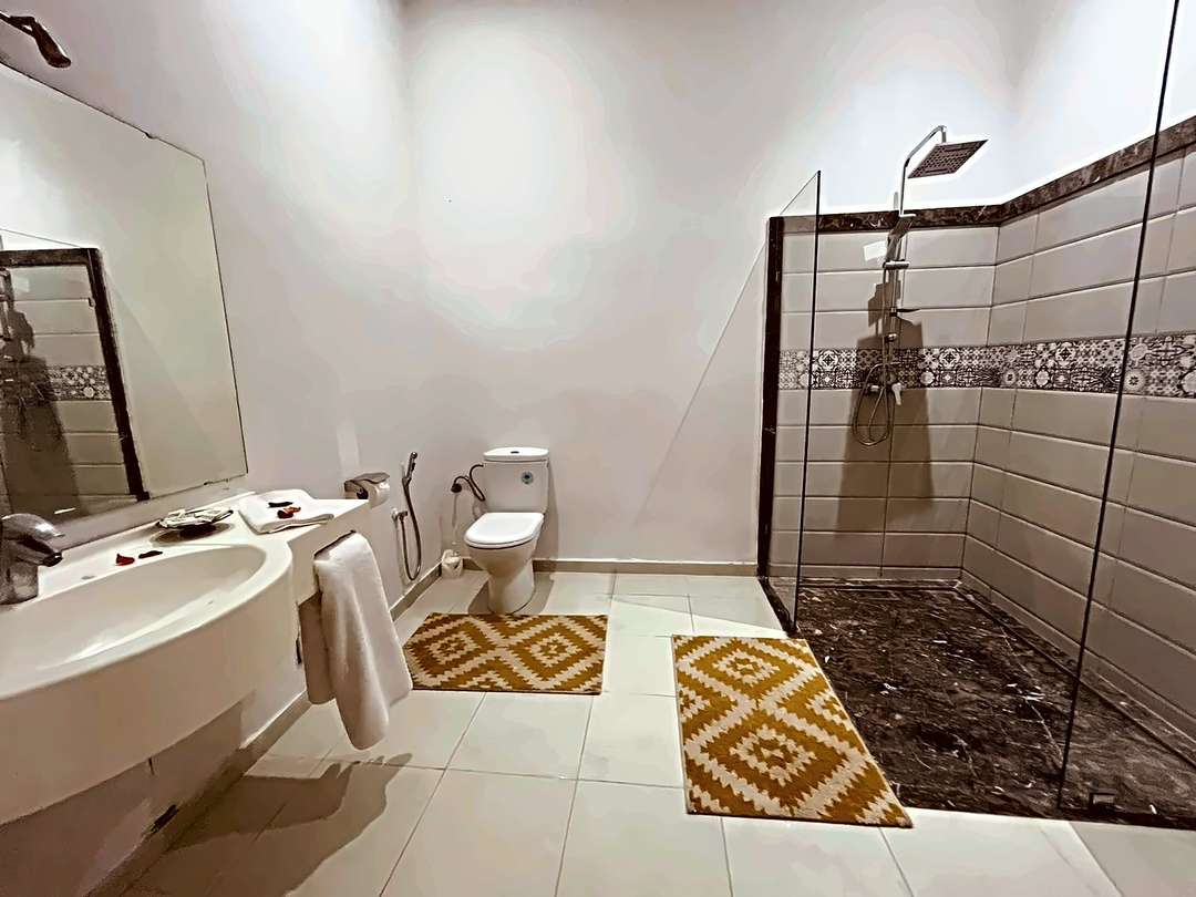 Sala d’acqua con parete di vetro, fascia di piastrelle a motivi e un grande lavabo