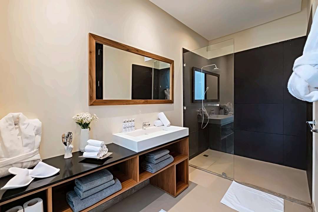 Badezimmer mit Waschtisch aus Walnussholz, weißem Waschbecken, Teakspiegel und ebenerdiger Dusche