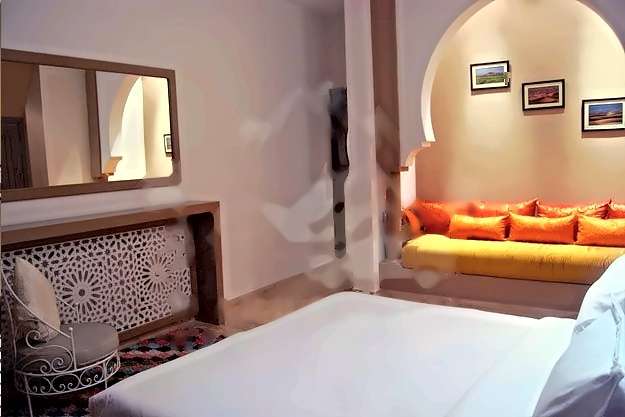 Schlafzimmer mit gemusterter Konsole, Spiegel und einer Sitznische unter einem Bogen