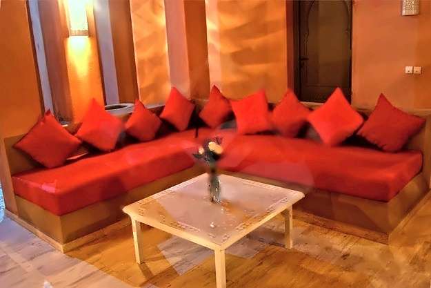 Salon mit eingebauten roten Sofas, roten Kissen und einem Mosaik-Couchtisch
