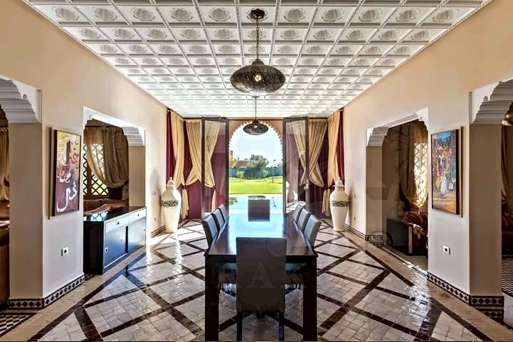 Sala da pranzo sotto un soffitto di stucco cesellato, con tavolo per dieci e porte aperte sulla piscina