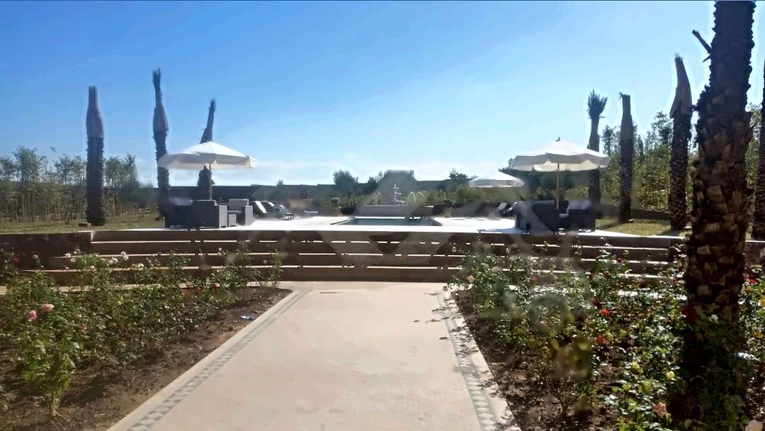 Un vialetto piastrellato tra le aiuole di rose fino alla piscina di Villa Izuran