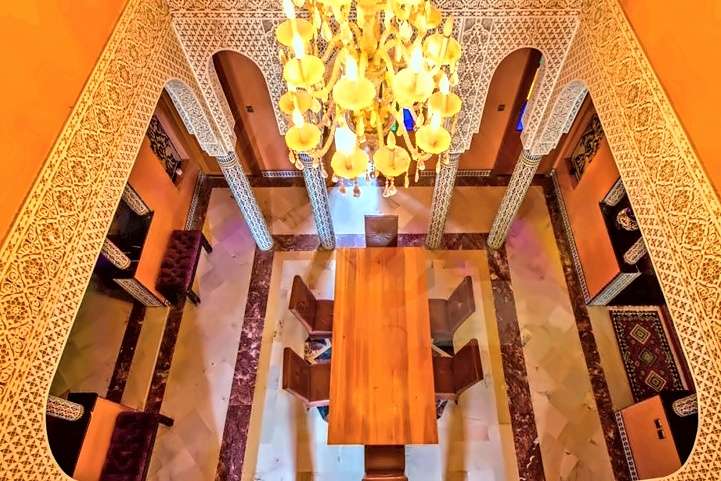 Sala da pranzo vista dall’alto, sotto un grande lampadario, con archi di stucco cesellato