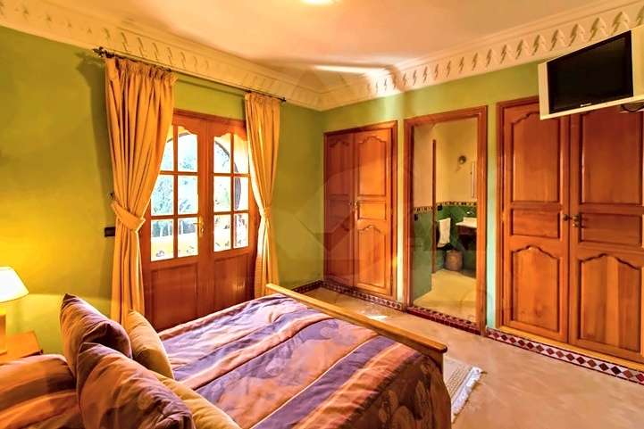 Camera verde con letto matrimoniale, una porta-finestra ad arco e una porta sul bagno