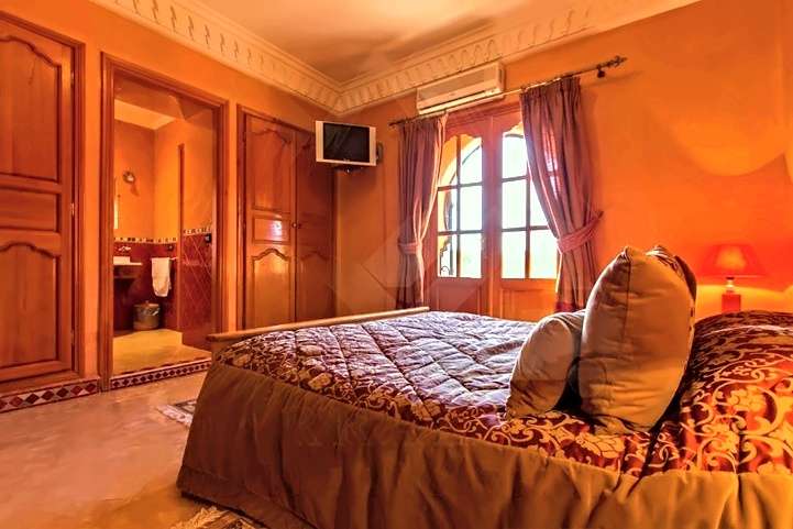Camera arancione con letto matrimoniale, armadi di legno e una porta sul bagno privato