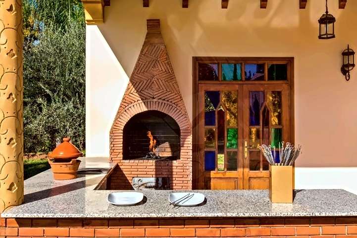 Cucina esterna con barbecue in mattoni, piano di lavoro in granito e una tajine